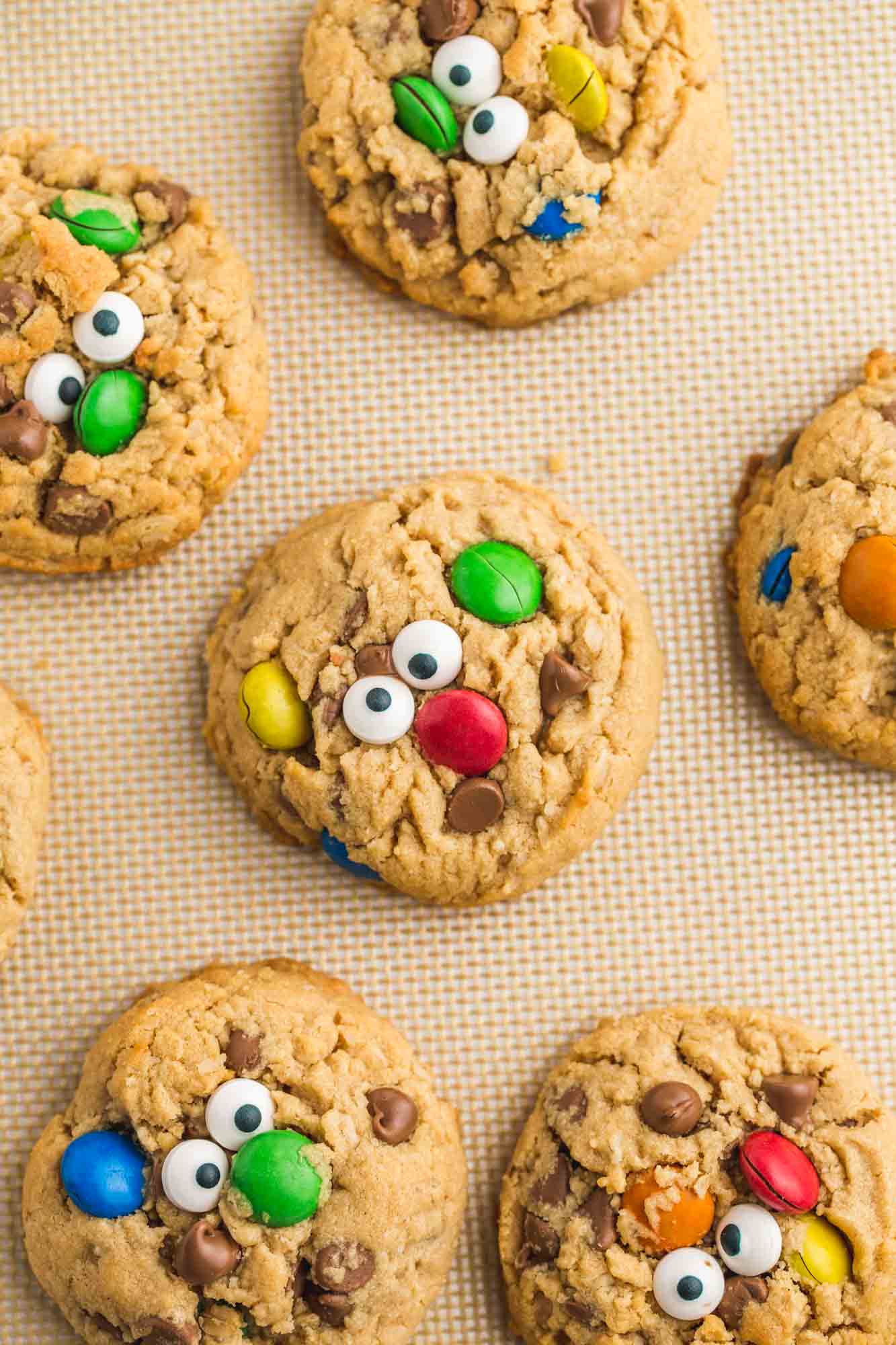 Overhead shot of monster cookies with edible eyes placed on a silicone baking mat
