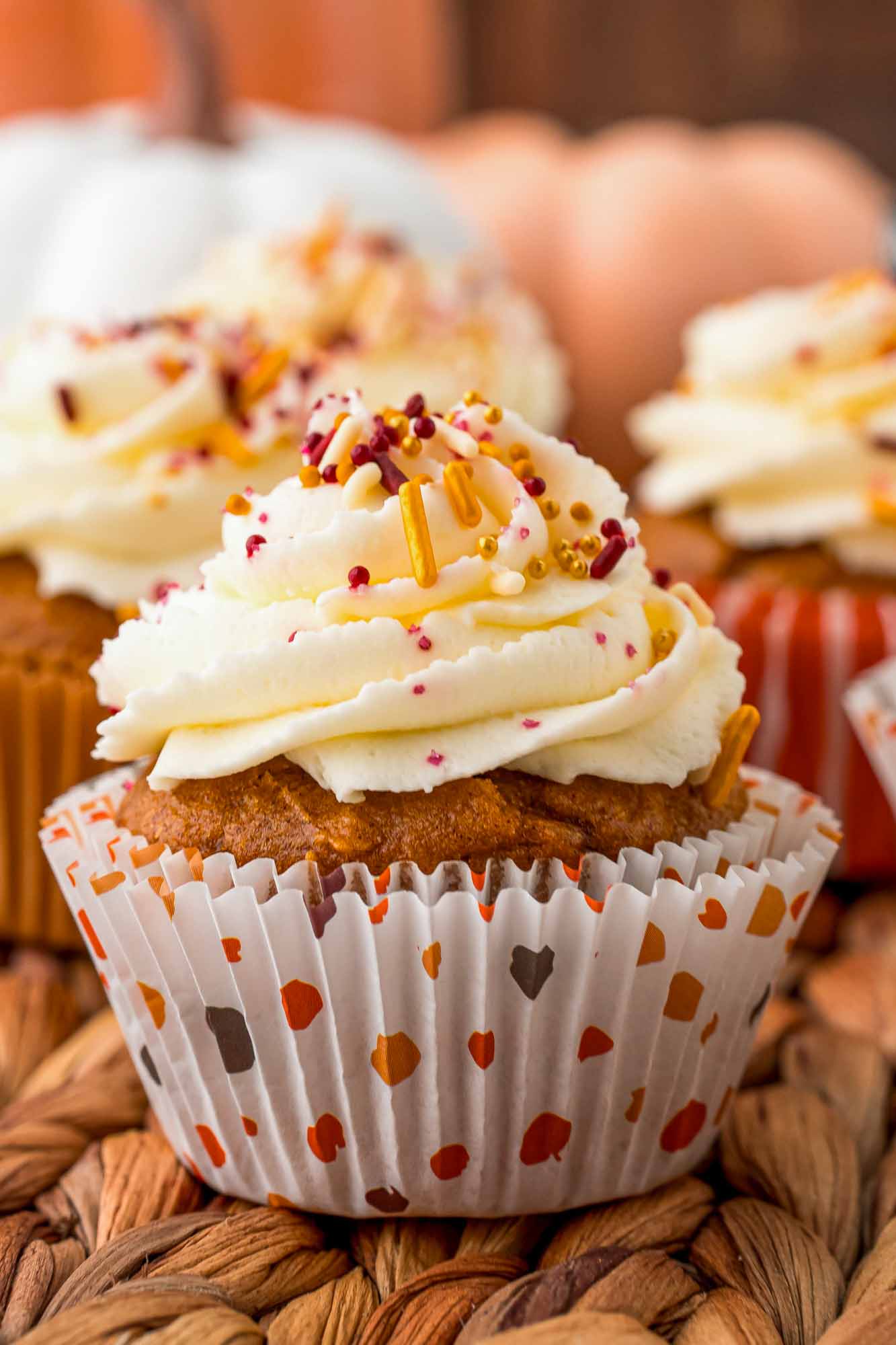 Close up shot of a pumpkin cupcake with vanilla frosting and sprinkles