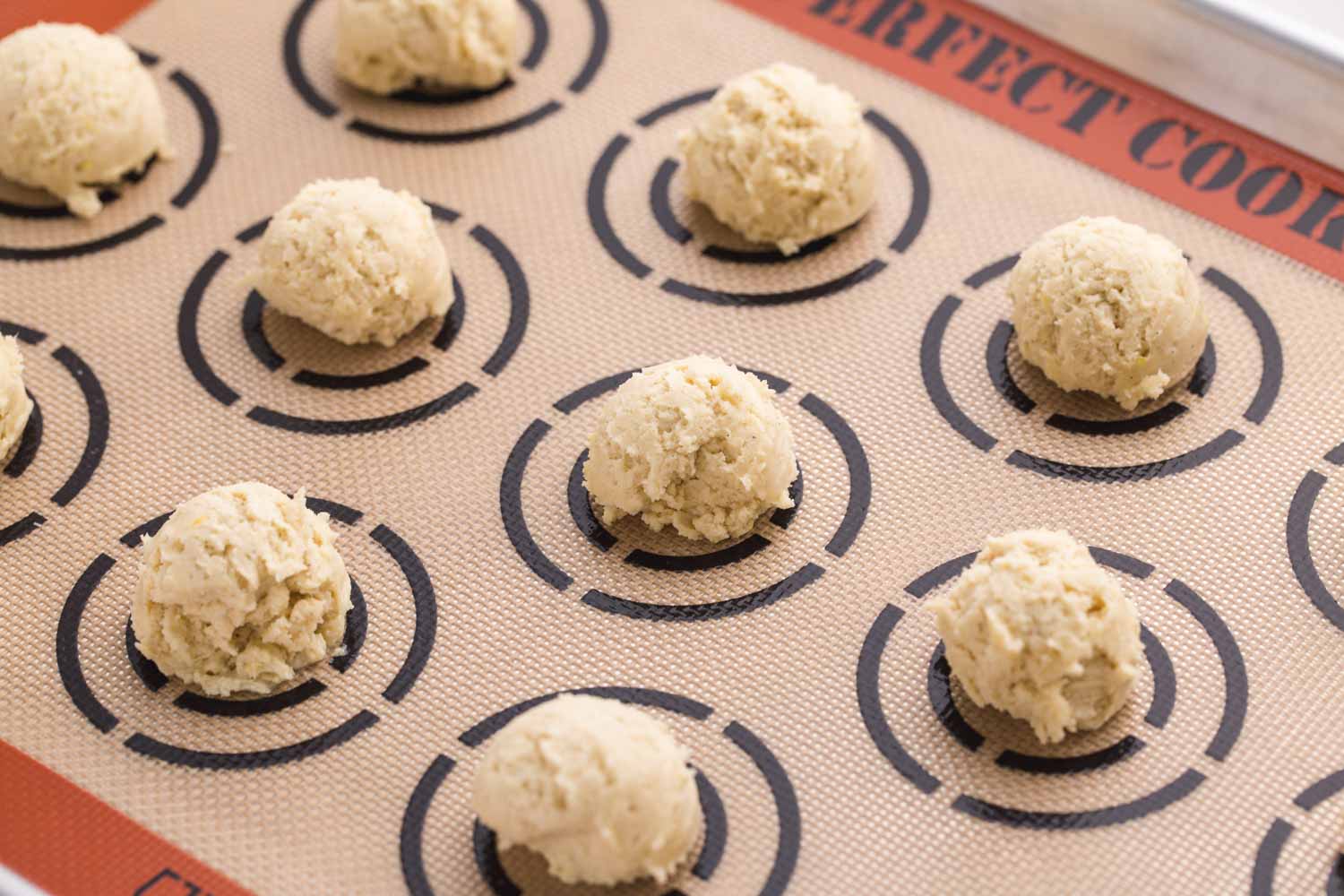 Cookie dough balls on a silicone mat before baking