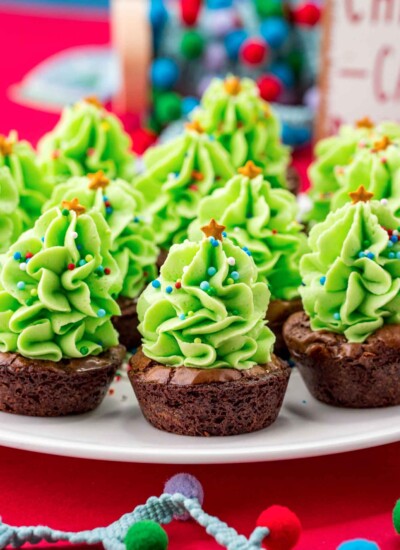 Christmas Tree Brownie Bites served on a white platter, with a red background.
