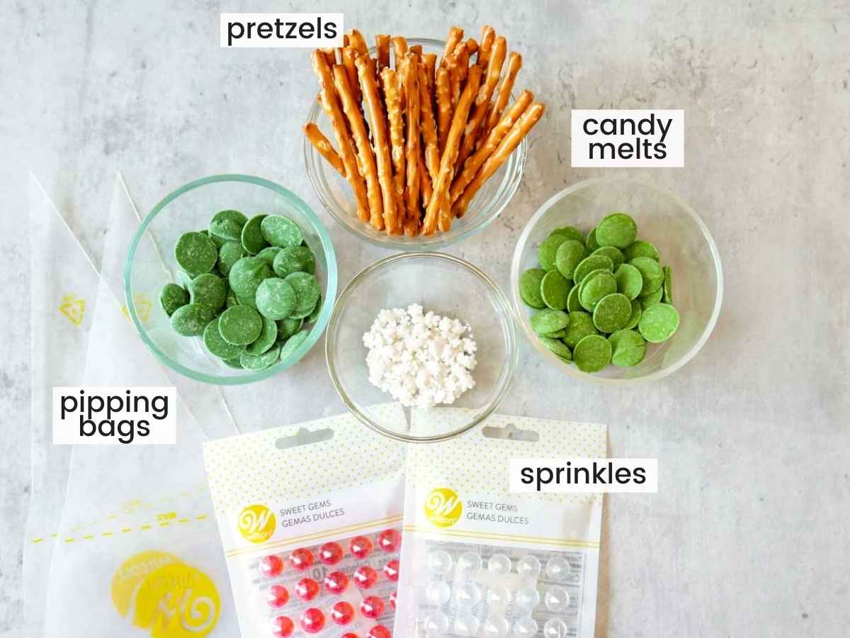 Ingredients needed to make Christmas tree candies, including pretzels, candy melts, and sprinkles.