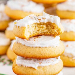 5 eggnog cookies with frosting stacked on top of each other. The top one has a bite missing