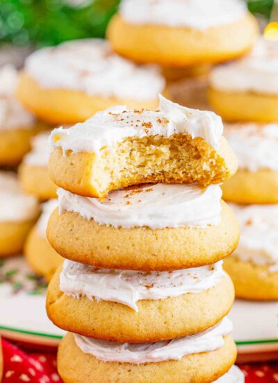 5 eggnog cookies with frosting stacked on top of each other. The top one has a bite missing