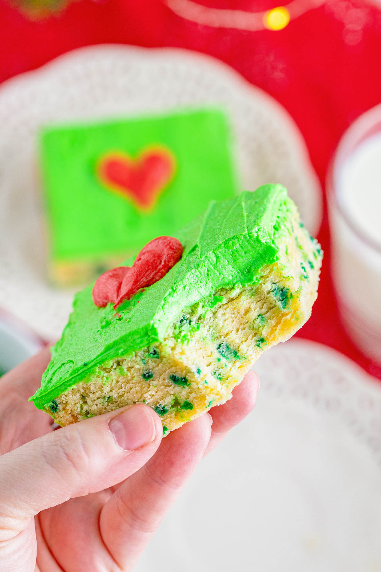 a hand holding a grinch cookie bar with a bite taken out of it.