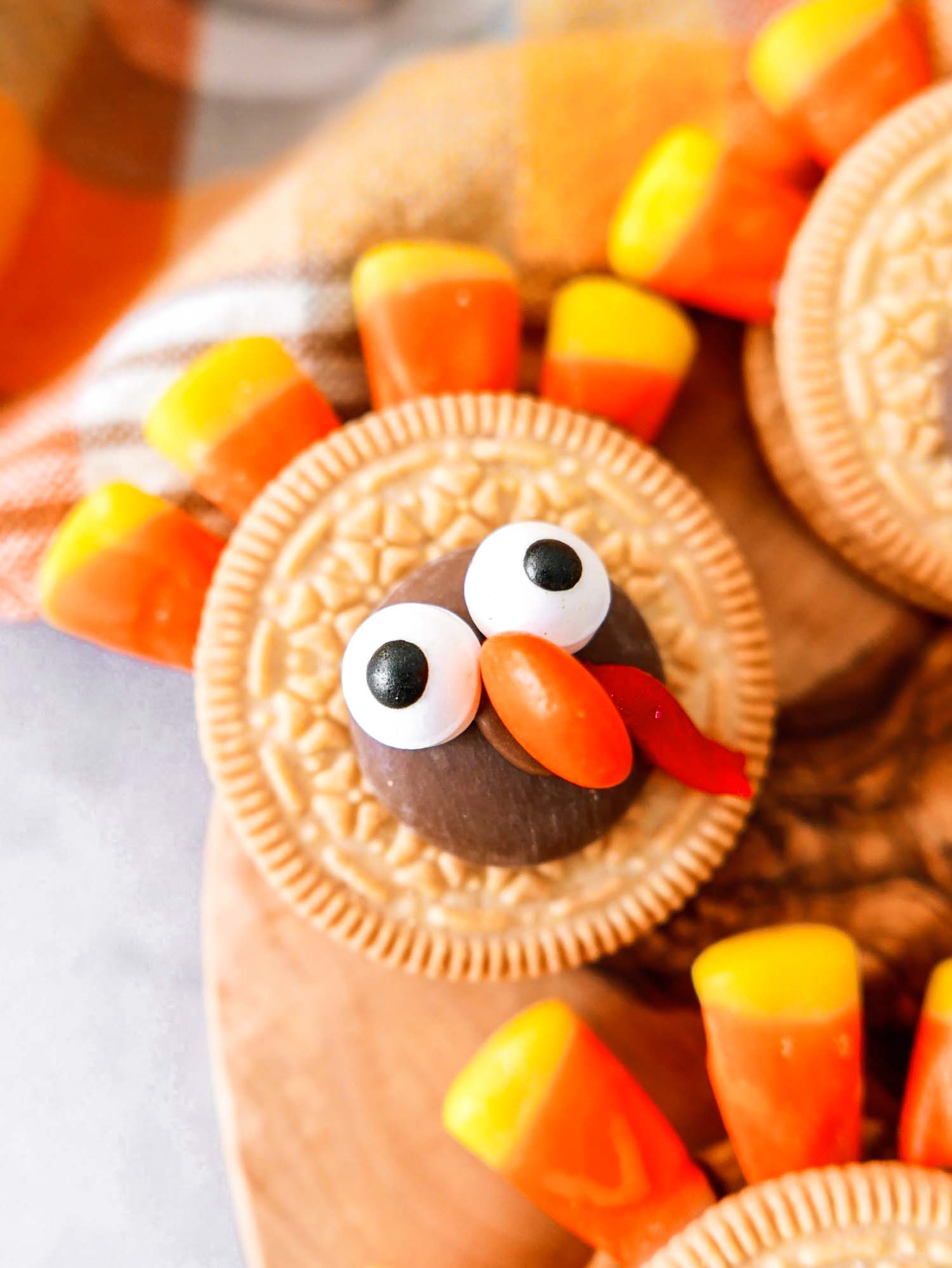 a golden oreo cookie decorated to look like a turkey with a hersheys kiss and candy corn