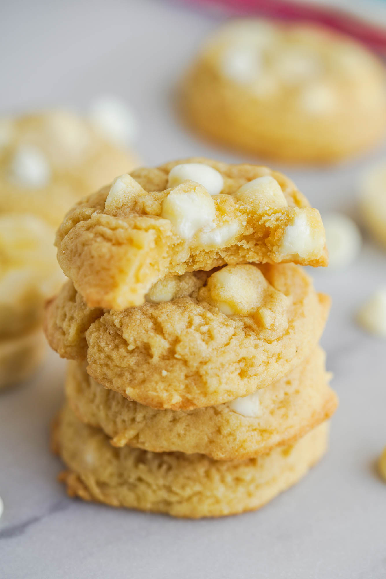 a stack of four banana pudding cookies with a bite missing from the top one. 