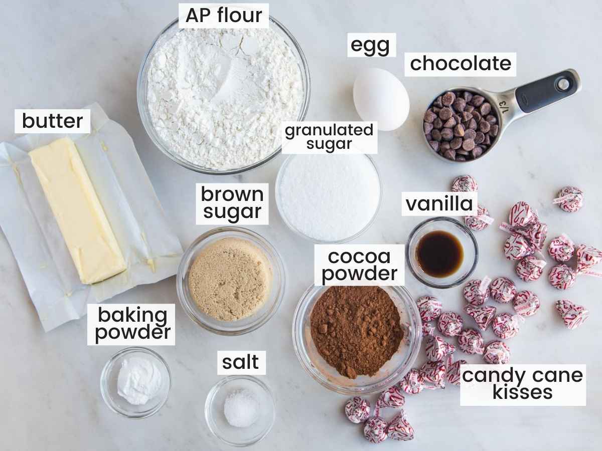 labeled image of all of the ingredients for peppermint kiss cookies laid out on the counter in separate small bowls. 