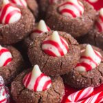 Chocolate Blossom Cookies with Peppermint hershey's kisses, on a red and white plate with candy canes on the side