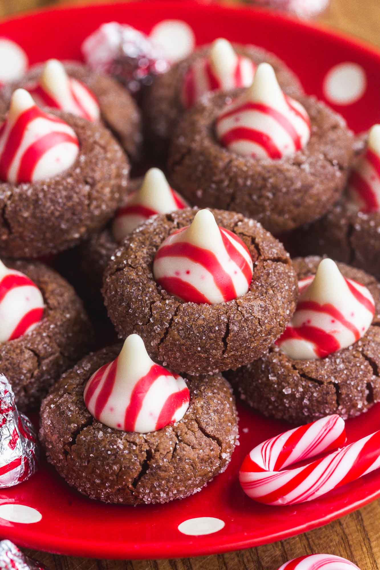 Chocolate Blossom Cookies with Peppermint hershey's kisses, on a red and white plate with candy canes on the side