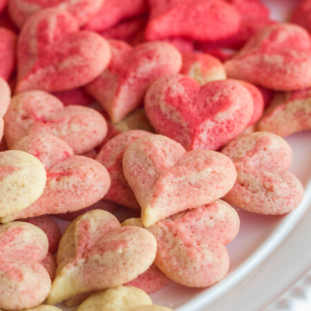 Heart shaped spritz cookies aranged in an ombre white to pink color pattern