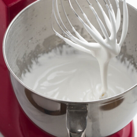 Royal icing in a red kitchenaid mixer with a metal bowl.