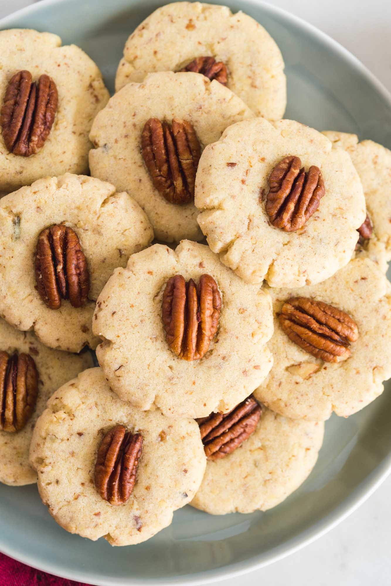 a plate of homemade pecan sandies cookies with whole nuts on top of each. 