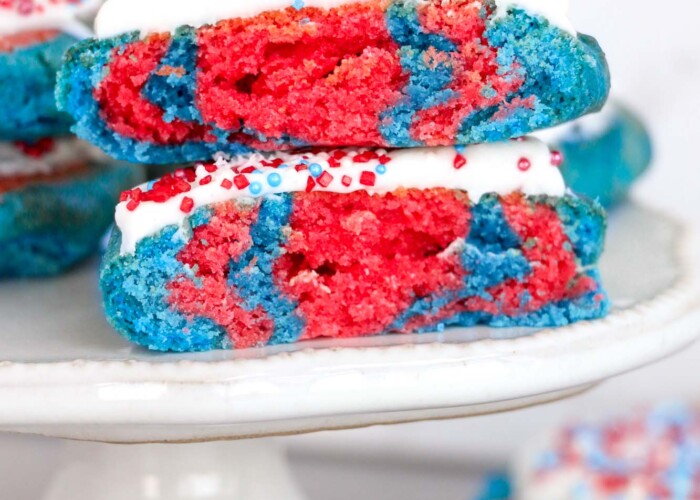 2 patriotic cookies frosted and served on a small white cake stand.