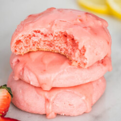 Three strawberry cake mix cookies stacked. The top cookie has a bite taken to show the texture inside.