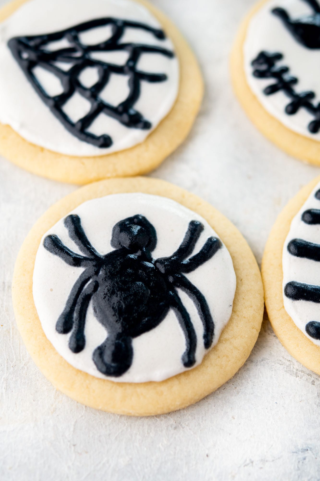 two round halloween sugar cookies decorated with spiders and spider webs