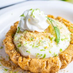 copycat crumble key lime cookie on a plate topped with a piece of lime and whipped cream