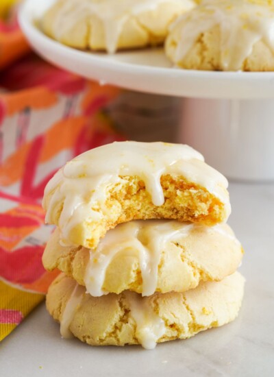 a stack of lemon cookies with glaze. A bite has been taken of the top cookie