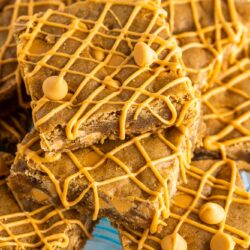 A stack of butterscotch blondies topped with a drizzle of melted butterscotch chips.