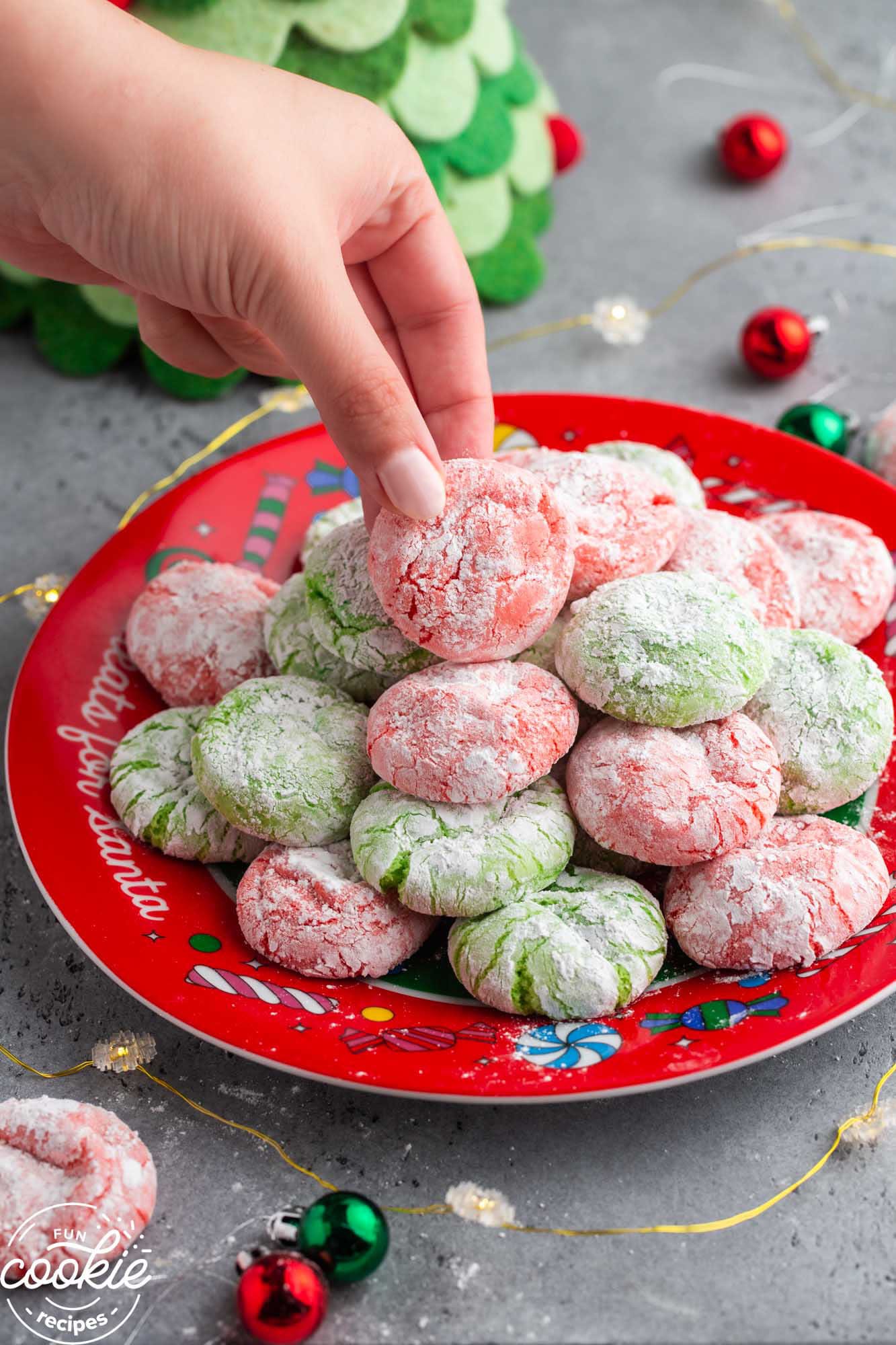 Taking a red Christmas crinkle cookie from a cookie tray