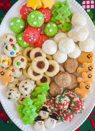 7 different christmas cookies served on an oval white platter, overhead shot.