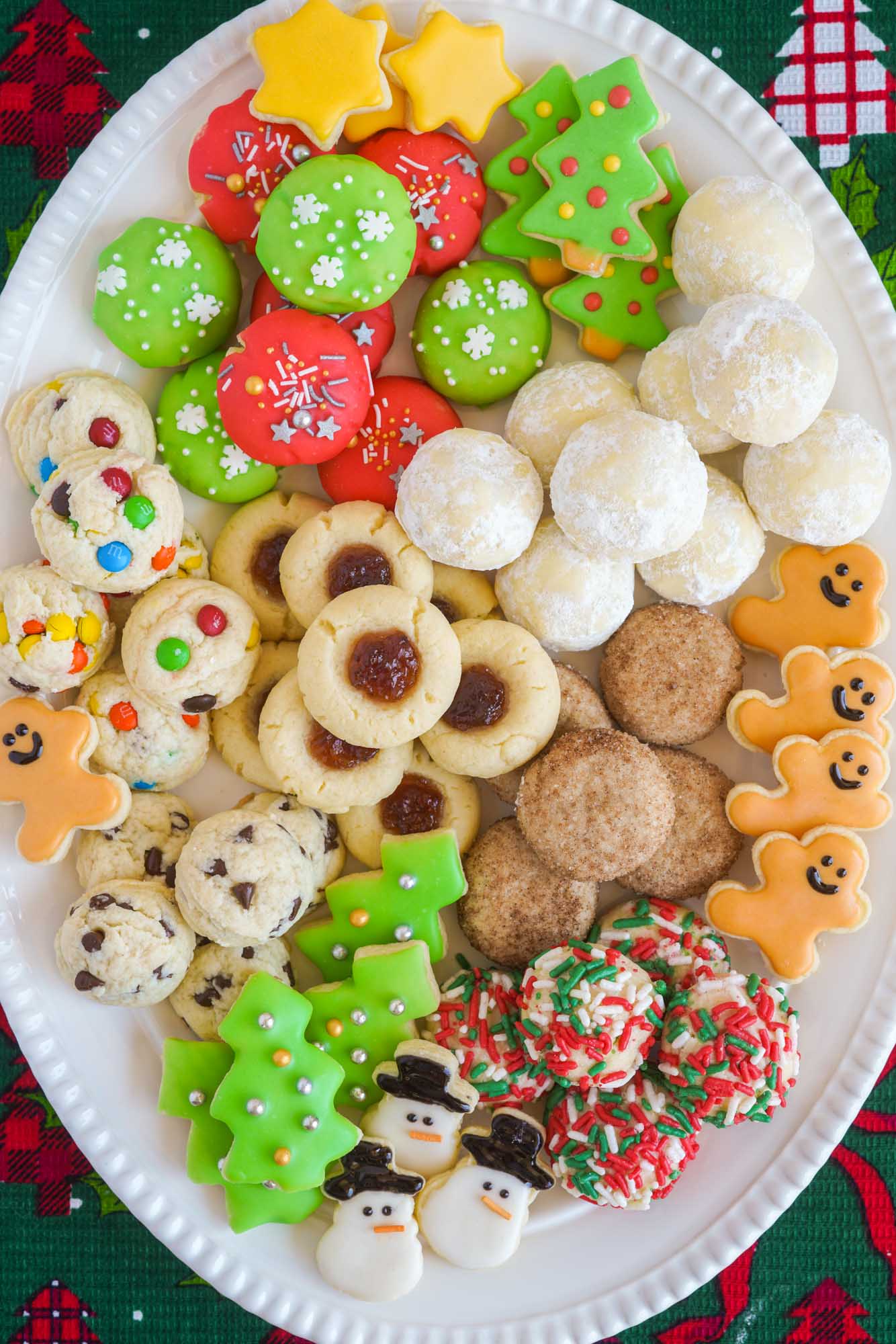 7 different christmas cookies served on an oval white platter, overhead shot.