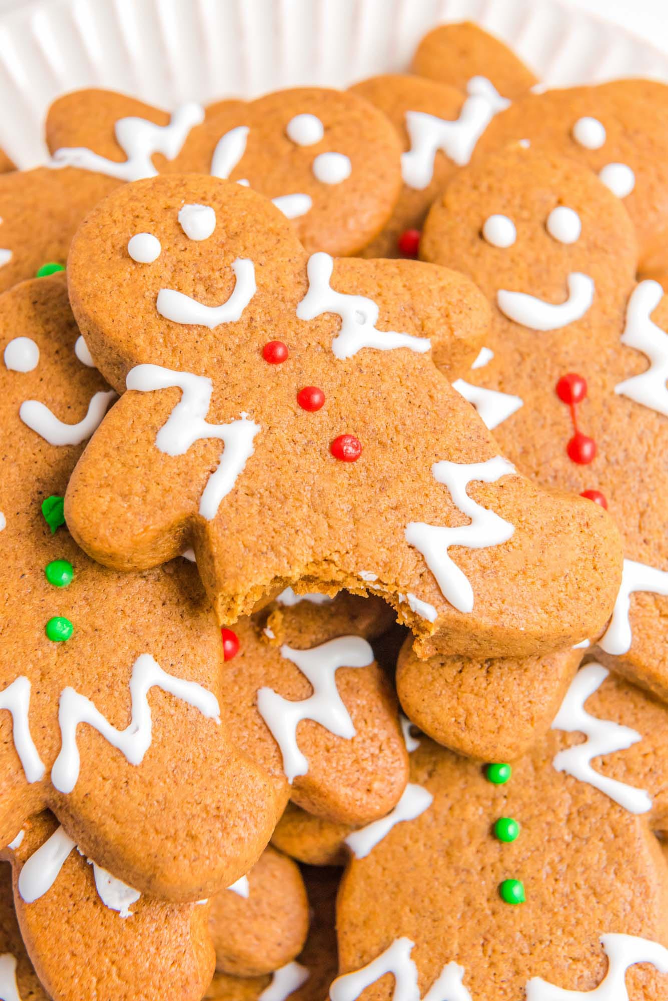 Closeup image of gingerbread cookies. The gingerbread man on top of the pie has a leg bitten off. 