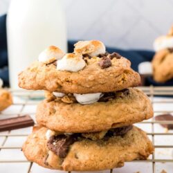 Three stacked S'mores cookies on a wire rack, with a bottle of milk in the background.