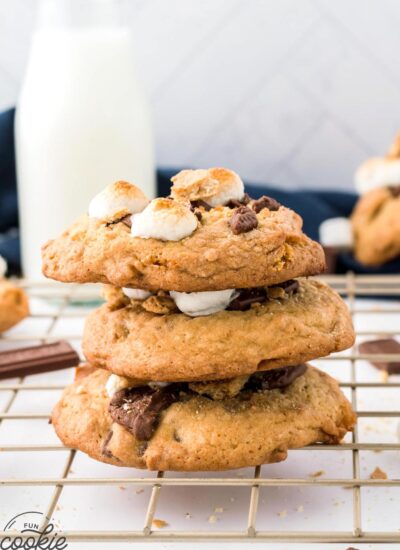Three stacked S'mores cookies on a wire rack, with a bottle of milk in the background.
