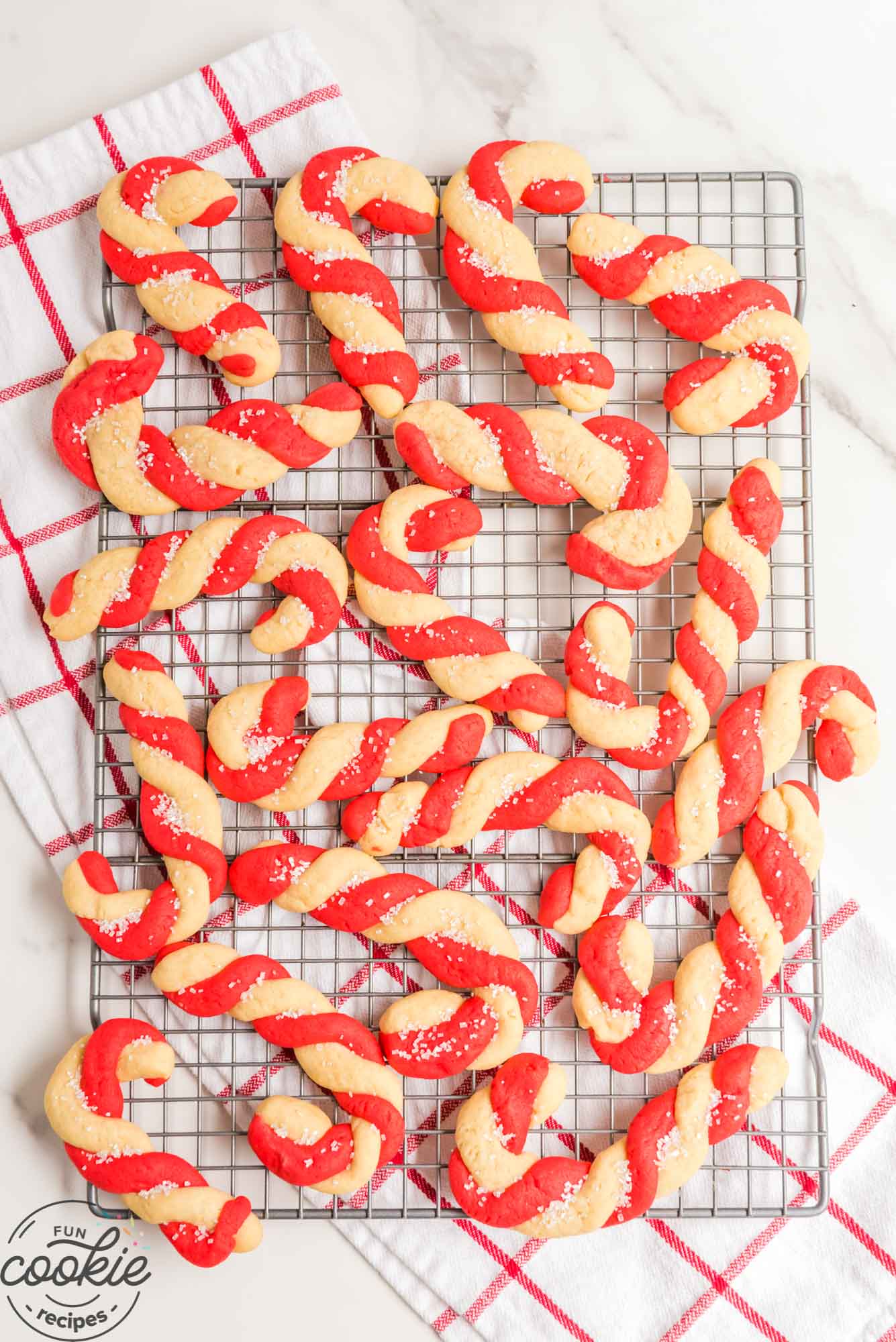 Red and white candy cane cookies made with two colors of dough, on a wire rack, cooling.