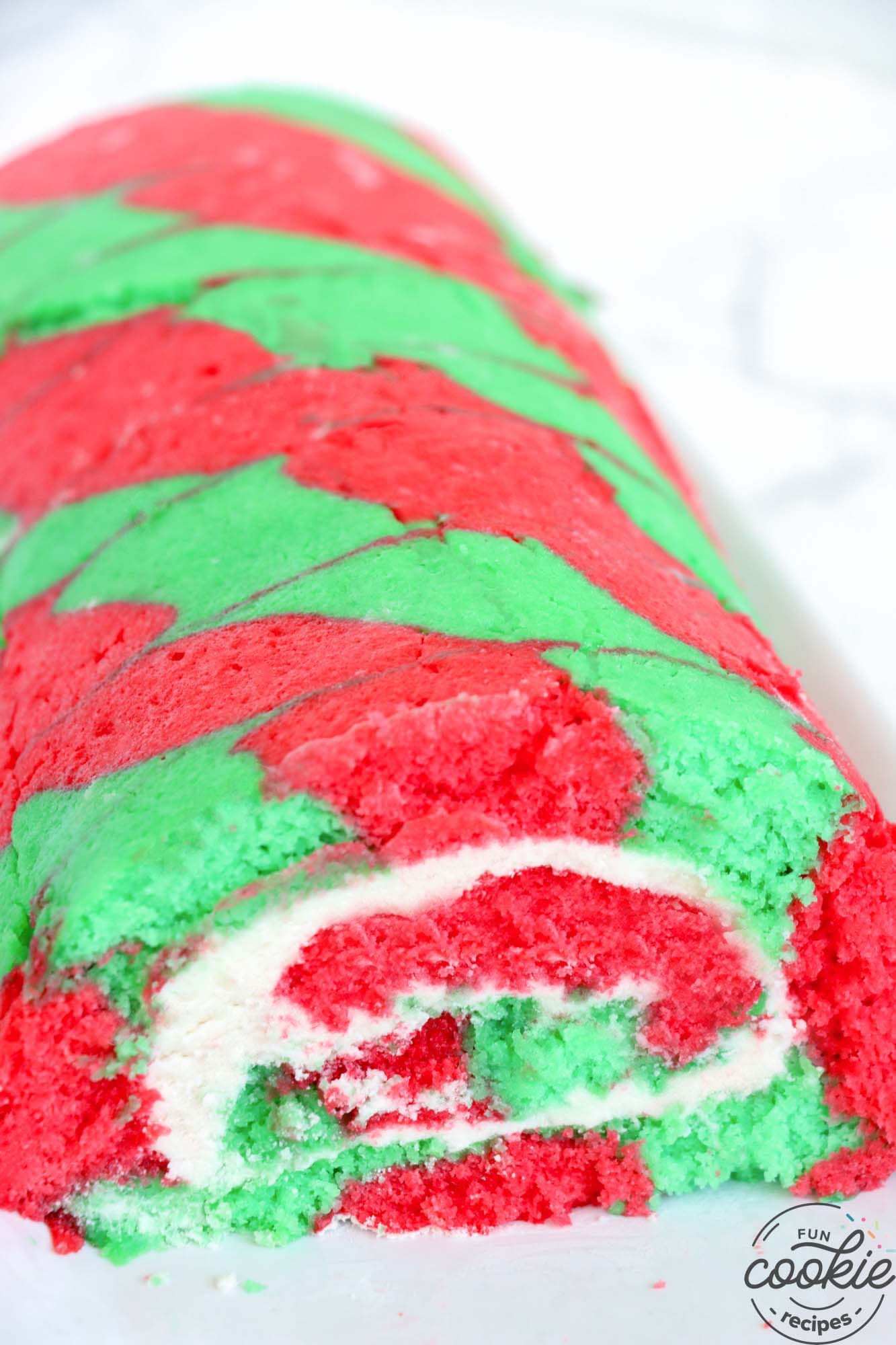 A red and green christmas cake roll before slicing