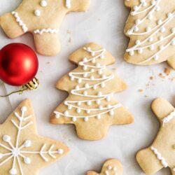 Overhead shot of shortbread christmas cookies with icing, and a red Christmas ornament