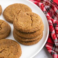 A stack of gingersnap cookies, with christmas decorations in the background