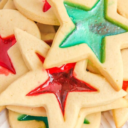closeup of cut out star stained glass cookies with red and green candy windows.