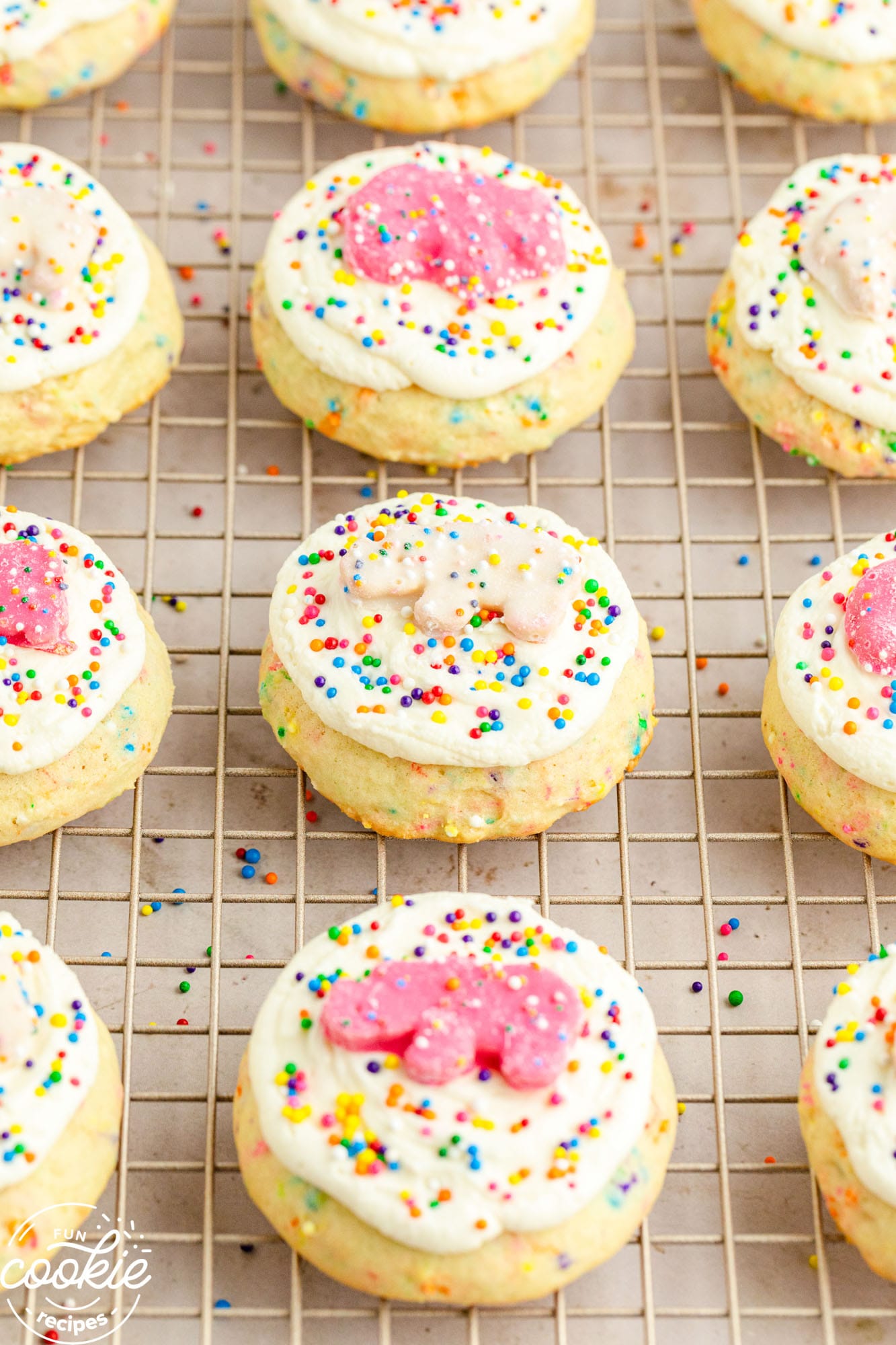 a wire rack holding sprinkle sugar cookies with icing and frosted animal cookies on top.