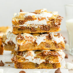 Three smores cookie bars with chocolate and marshmallows, stacked on top of each other.