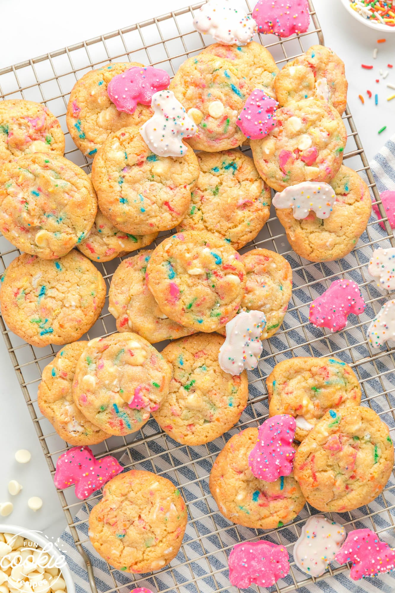 a wire cooling rack of cookies with pink and blue sprinkes inside, and frosted animal cookies.
