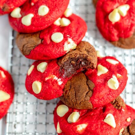 Brookies that are half brownie half red velvet cookie with white chocolate chips, spread out on a wire rack.