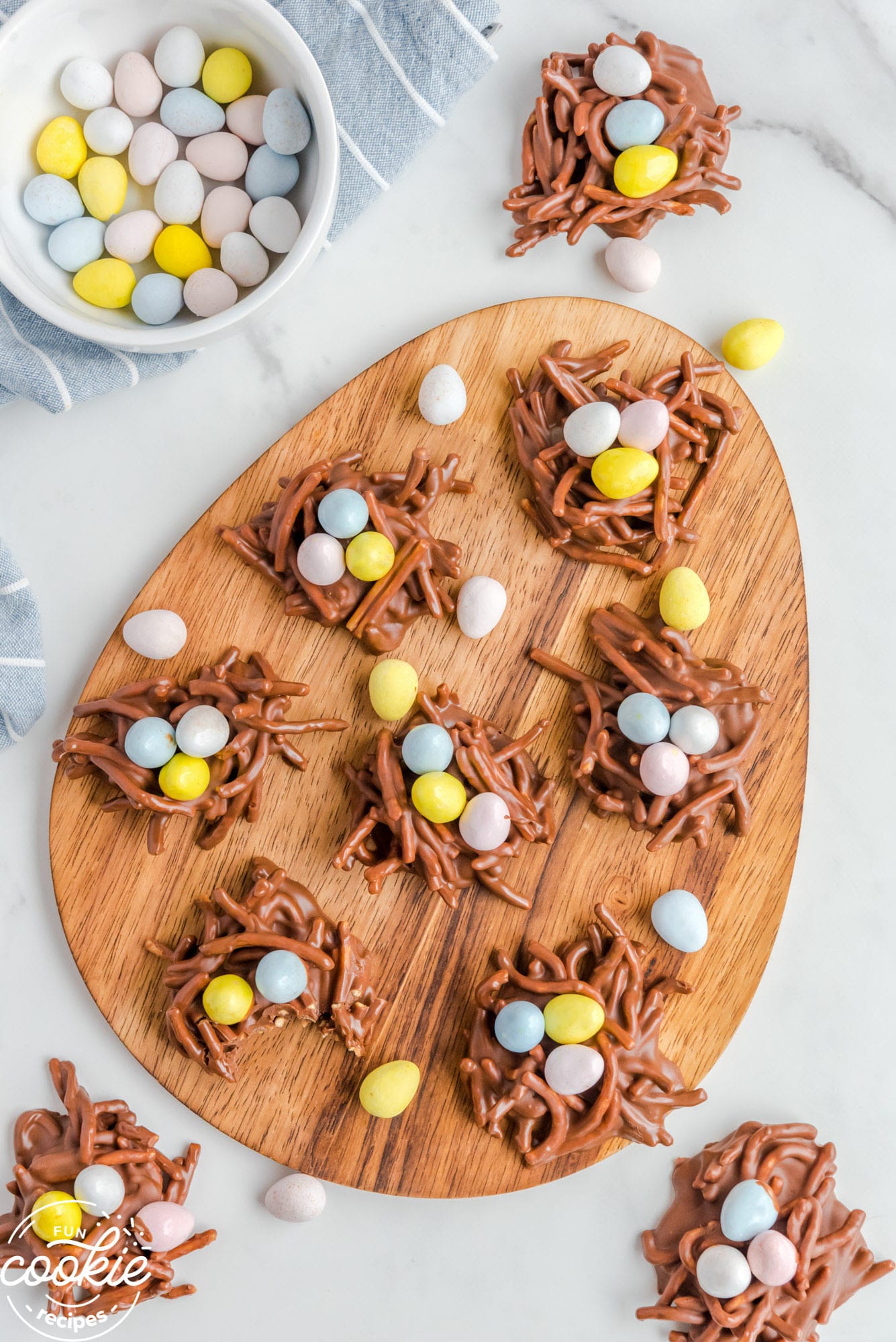 Birds nest cookies on an easter egg shaped wooden board.