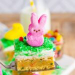 A cookie bar with frosting, green coconut flakes, and a pink peeps bunny on top.