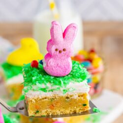 A cookie bar with frosting, green coconut flakes, and a pink peeps bunny on top.