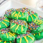 Football cookies stacked on a white plate, with a glass of milk in the background.