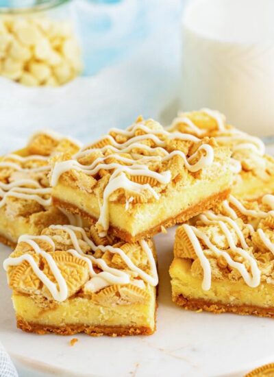 Cheesecake bars served on a white marble plate, and a glass of milk in the background