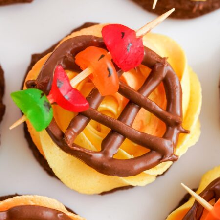 bbq grill cookie with orange frosting, chocolate grate, and gummies on a toothpick to make a kabob decoration.
