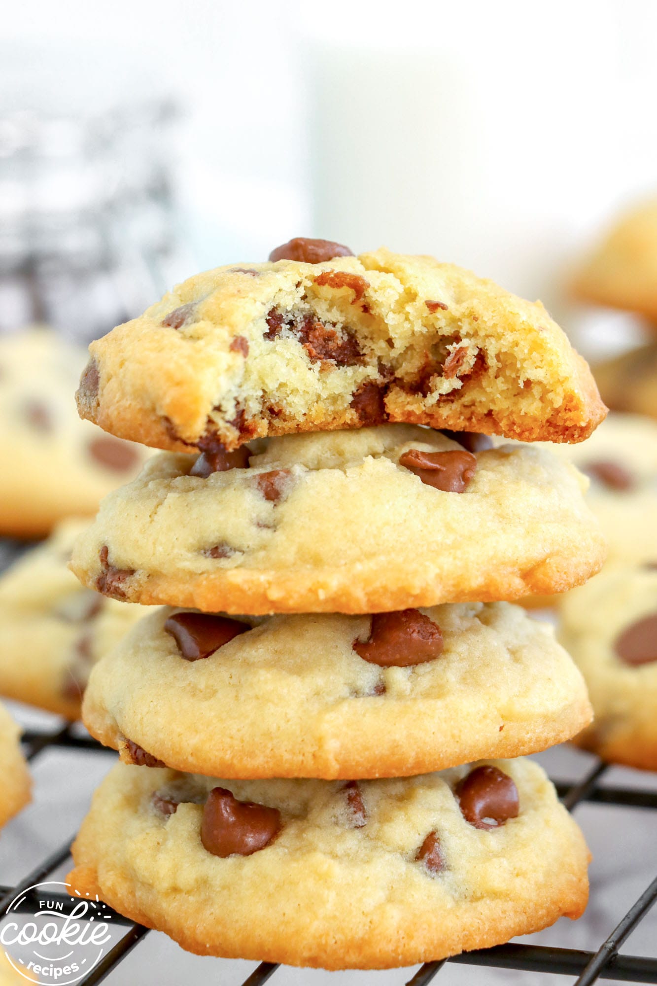 a stack of four chocolate chip cookies with a bite taken from the top one.