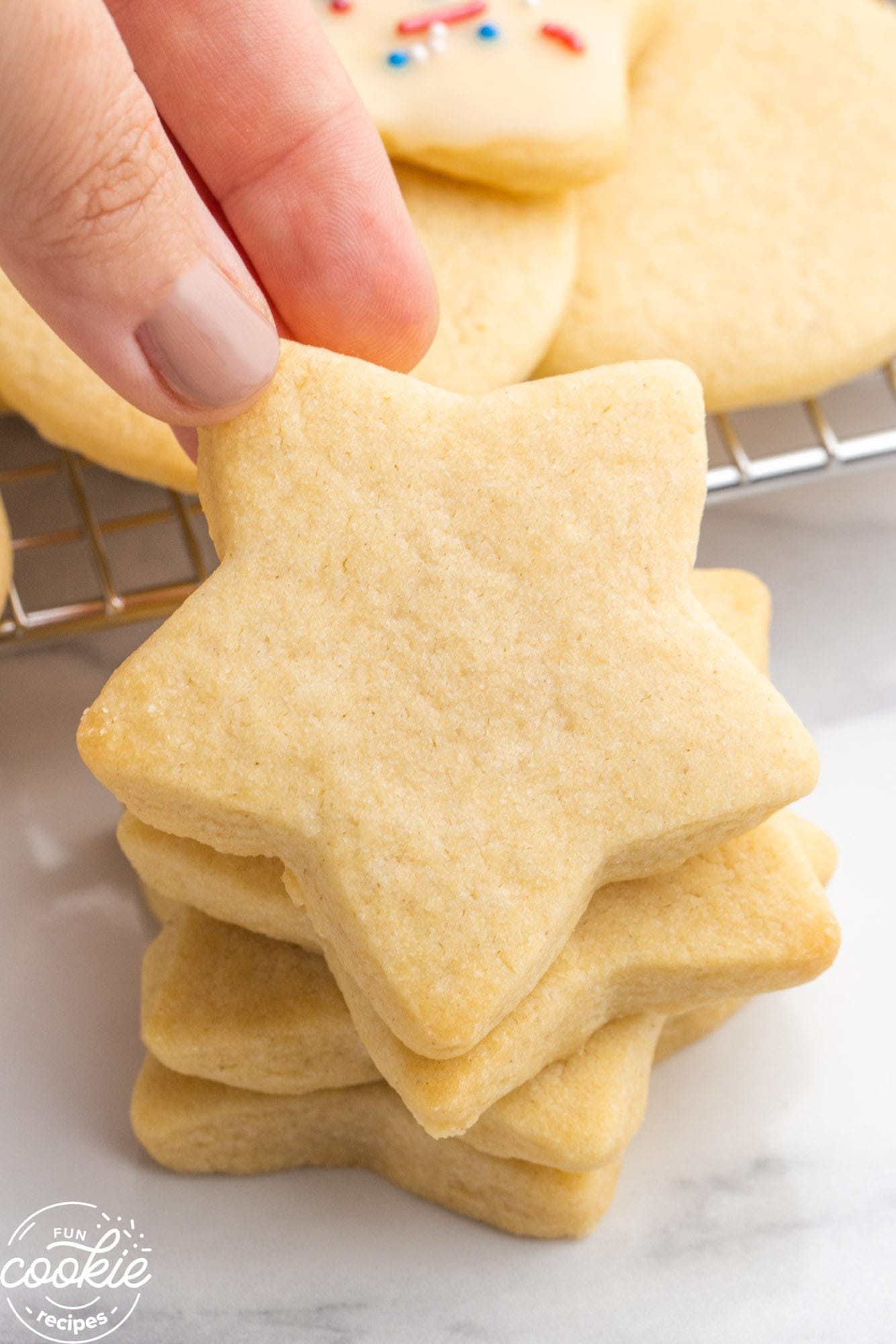 Stacked star sugar cookies, and a hand holding one cookie.