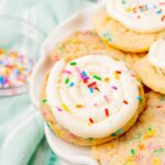 a plate of sugar cookies. The ones on top are covered with buttercream frosting and colorful sprinkles.