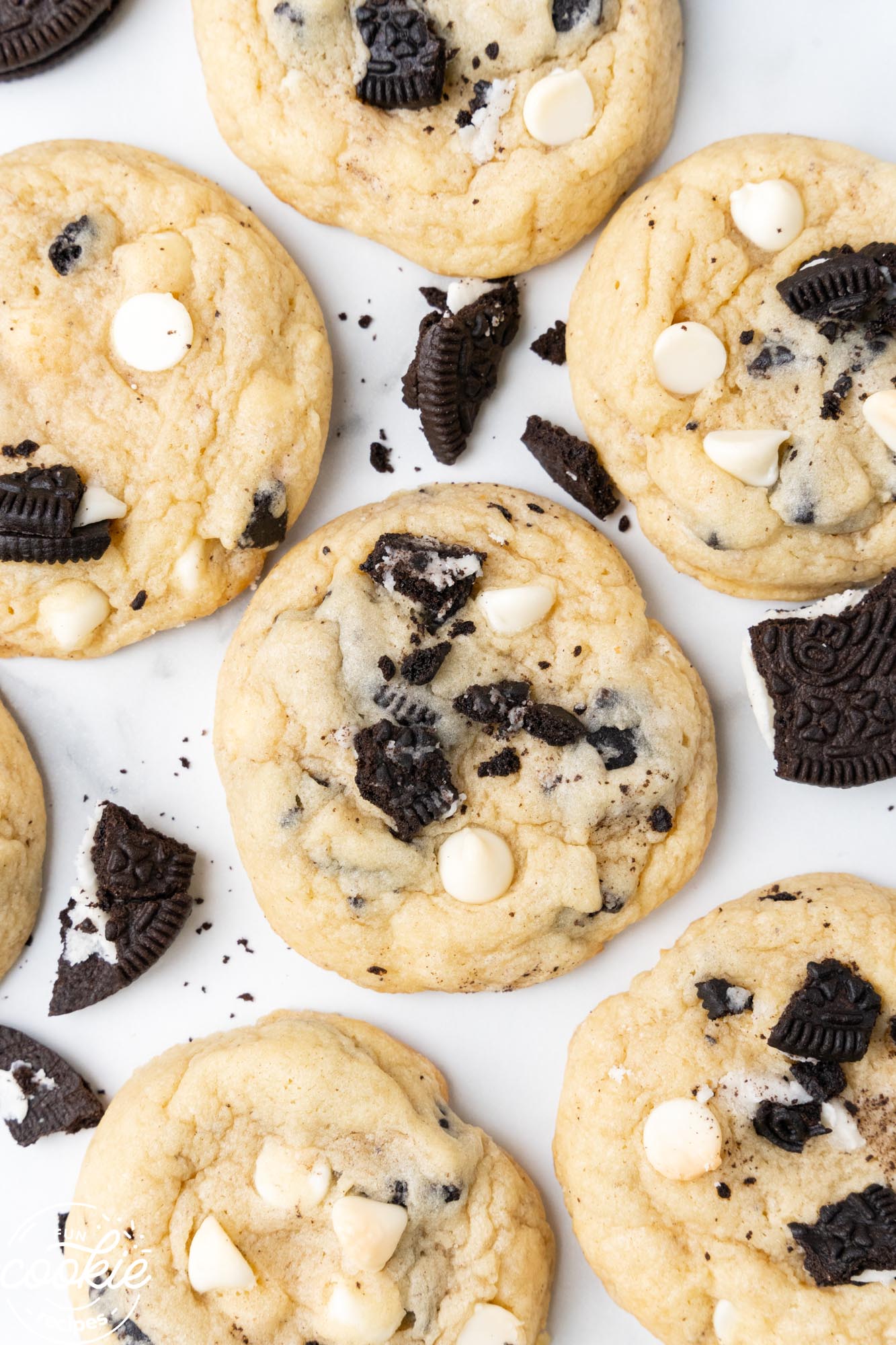 cookies with white chocolate chips and crushed oreos, on a white countertop.