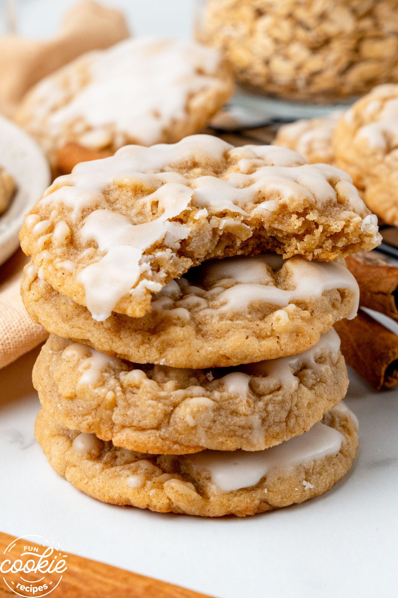 a stack of four iced oatmeal cookies. the top one has a bite taken out.