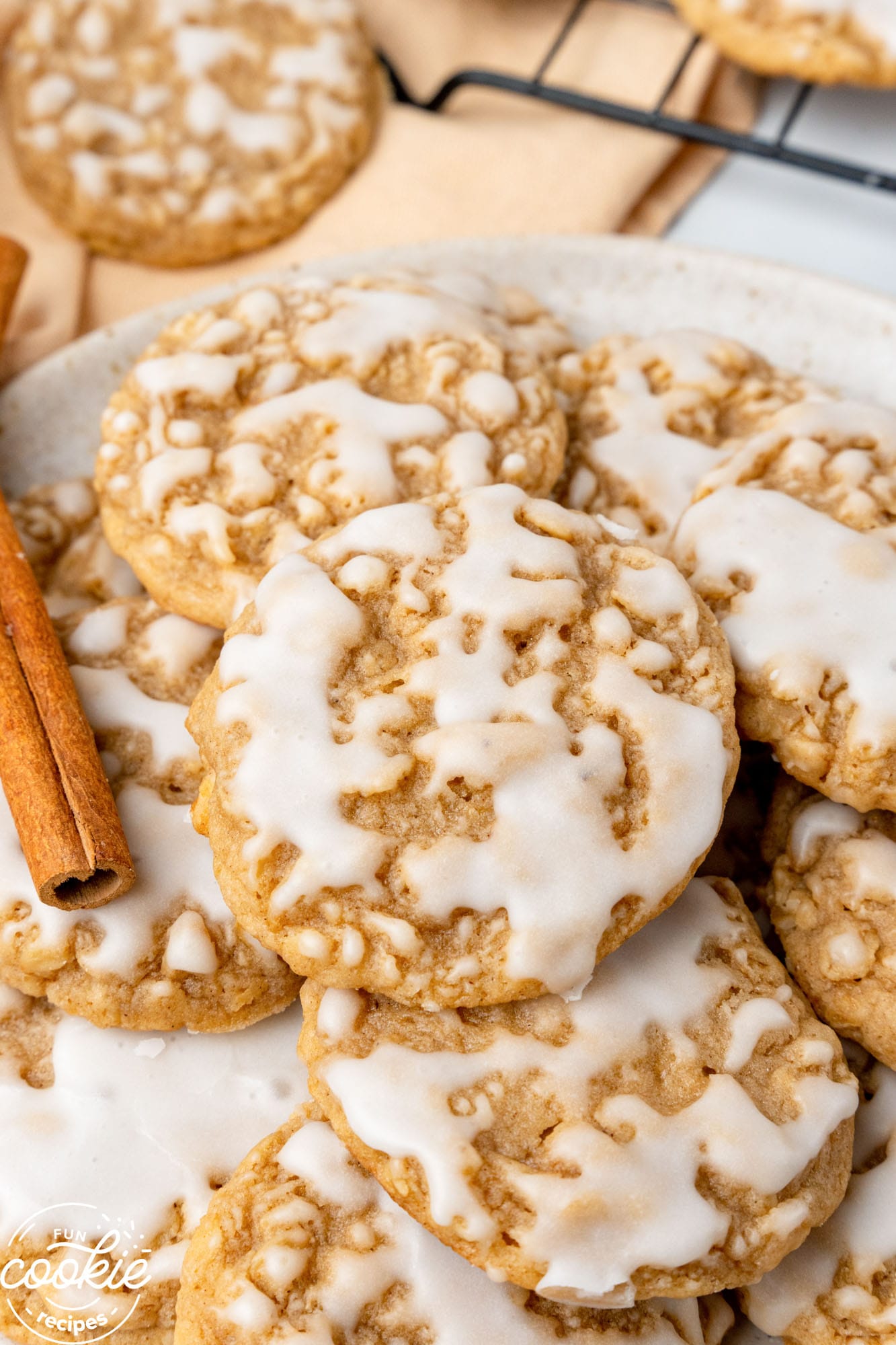 iced oatmeal cookies on a plate, garnished with a cinnamon stick.