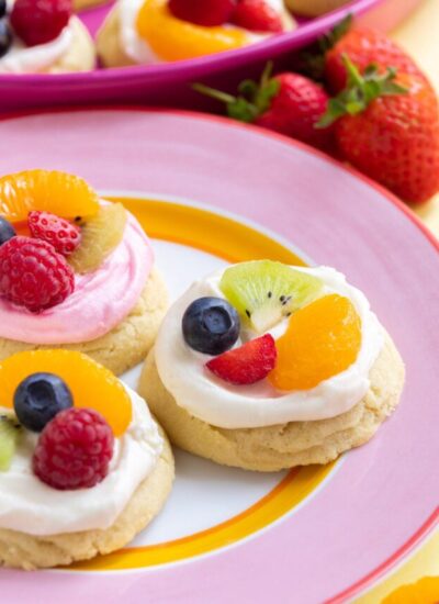three fruit pizza cookies on a pink plate.